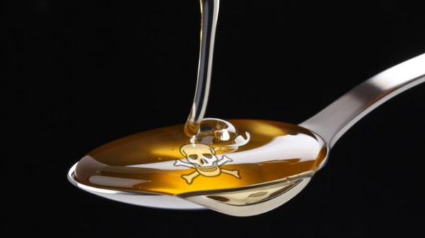 A spoonful of high fructose corn syrup with a skull and crossbones visible in the syrup. Image credit: yournewswire.com