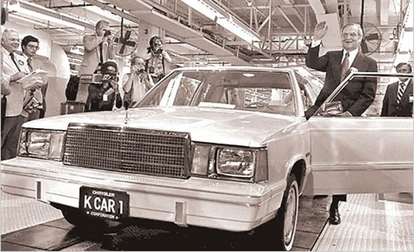 black and white photo of 
        Lee Iococa driving the first Chrysler K Car off of the assembly line
